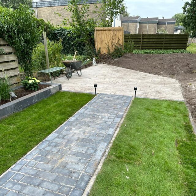 Een elegant tuinpad omringd door groen, met subtiel verlichte lantaarns en een rustgevend stenen platform.